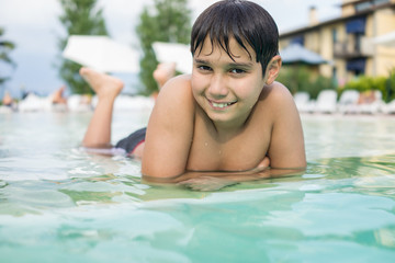 Young boy kid child splashing in swimming pool having fun leisure activity