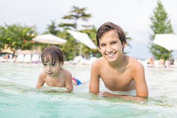 Fototapeta na wymiar Young boy kid child splashing in swimming pool having fun leisure activity