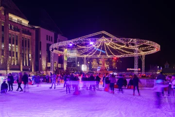Night view of people enjoy ice skating on temporary ice rink at Corneliusplatz and Schalenbrunnen in Düsseldorf during Christmas Market season in winter. in Düsseldorf, Germany. © Peeradontax