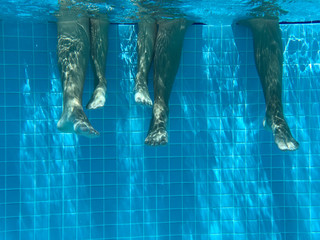 Legs of children in pool underwater