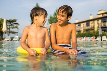 Fototapeta na wymiar Young boy kid child splashing in swimming pool having fun leisure activity