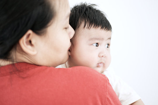 Young mother holding baby asian boy looking over shoulder : Closeup