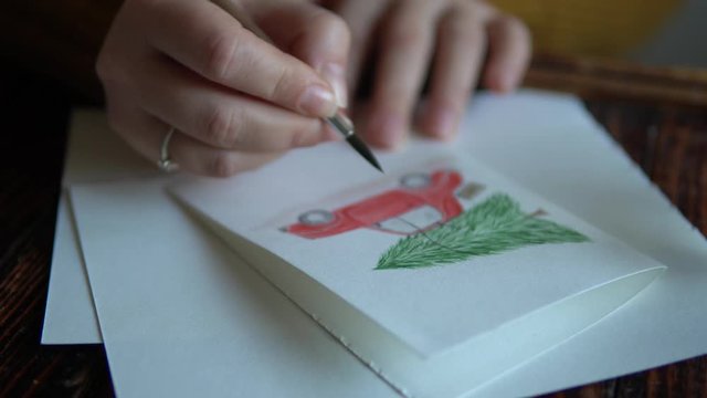 Woman painting red car with Christmas tree on the roof on the holiday postcard