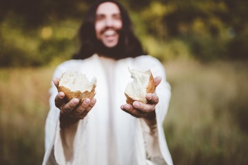 Shallow focus shot of Jesus Christ giving out a sliced breads