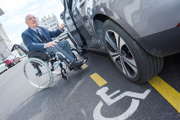 Fototapeta na wymiar senior man in wheelchair going into a car