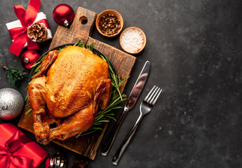Christmas-baked chicken or fried chicken with rosemary and cranberries, holiday gifts and toys on  background  stone Christmas dinner for the whole family, with copy space for your text