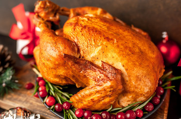Christmas baked chicken or fried chicken with rosemary and cranberries, holiday gifts and toys on  the background  stone Christmas dinner for the whole family