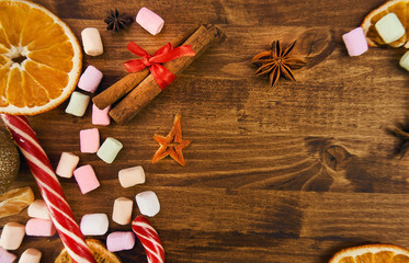  Christmas background on a tree located cinnamon with a red bow. along the perimeter are an orange, marshmallows and a New Year's caramel red and white cane.    