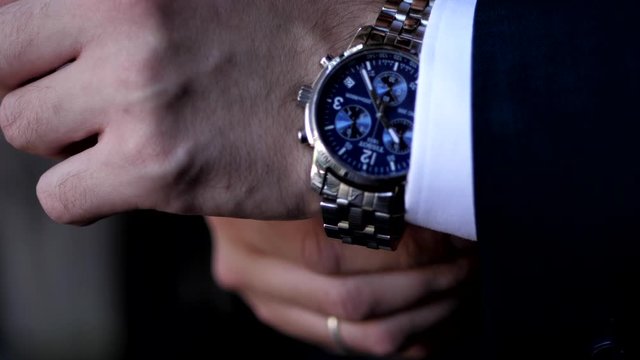 Groom In Dark Pantsuit Adjusts Modern Luxury Men Wrist Watch On Left Hand At Wedding Slow Motion Extreme Close View