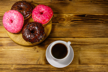 Cup of coffee and tasty donuts on a wooden table. Top view