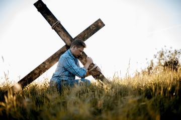 Shallow focus shot of a male carrying a handmade cross