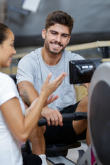 Fototapeta na wymiar female trainer assisting a man on rowing machine at gym