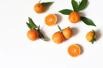 Selbstklebende Fototapeten Styled stock photo. Decorative summer fruit composition. Whole and sliced orange tangerines, citrus fruit and leaves isolated on white table background. Food pattern. Empty space. Flat lay, top view. © tabitazn