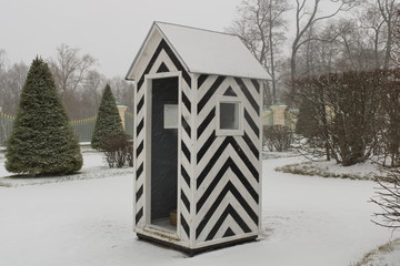 Black and white striped guardhouse in the middle of a snowy park close up