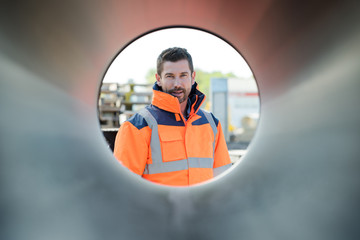 portrait of handsome construction worker framed through round tube