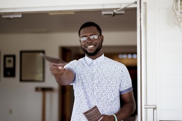 Shallow focus shot of a male holding a pamphlet towards the camera while smiling