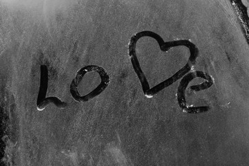 Inscription Love on white flour on a black background with a heart