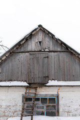 Naklejka premium Winter. Old village house, view from the outside of an attic from wooden planks. The roof is covered with snow