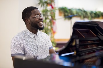 Shallow focus shot of a male smiling while playing the piano