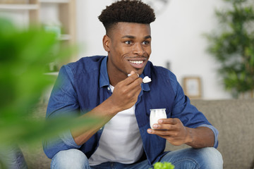cheerful young man eating yogurt for breakfast