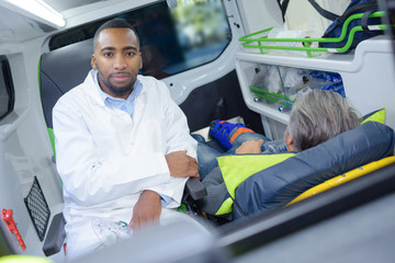 male doctor taking pulse of a man inside ambulance