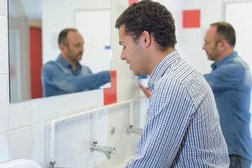 Fototapeta premium man washing hands in public toilet