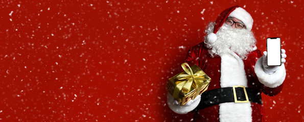 Happy Santa Claus in glasses hold gold present gift box and mobile cellphone with white screen for text space. Christmas concept © Dmitry Lobanov