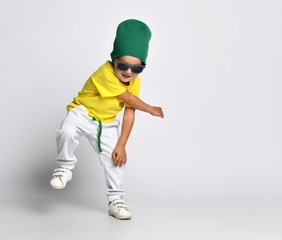 cheerful kid hipster boy in a green hat dancing in wide pants