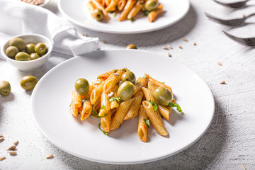 Plate with tasty pasta and olives on white table