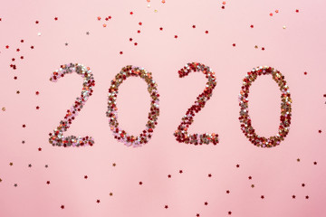 Numbers 2020 made of confetti on pink background. Christmas or New Year layout, flat lay, top view.