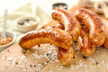 Tasty grilled sausages with spices on wooden board, closeup