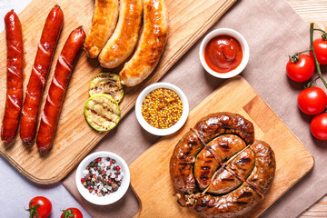 Wooden boards with tasty grilled sausages and sauces on table