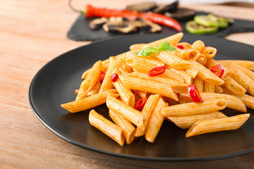 Plate with tasty pasta on wooden table, closeup