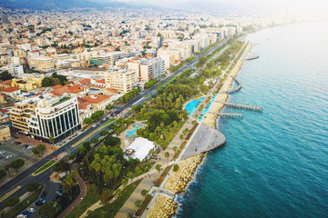 Obraz premium Limassol, Cyprus, aerial view at promenade or embankment. Famous Limassol walking alley with palms and wooden piers in resort town, drone photo.