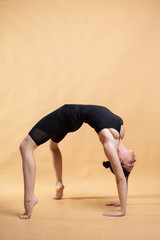Naklejka premium Side view portrait of beautiful young woman wearing white tank top working out against orange background, doing stretching.