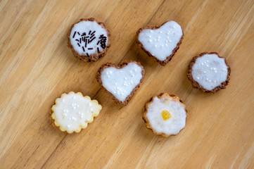 Jam and cream filled cookies with sugar sweet white icing on wooden table, group of Christmas sweets