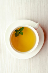 Cup and teapot of herbal tea with fresh mint on wooden