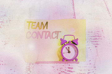 Word writing text Team Contact. Business photo showcasing The interaction of the individuals on a team or group Mini blue alarm clock stand tilted above buffer wire in front of notepaper