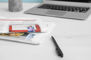 Newspapers and laptop on table