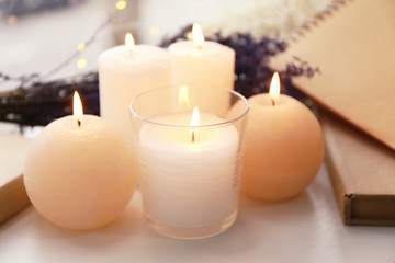 Beautiful burning candles and notebooks on window sill