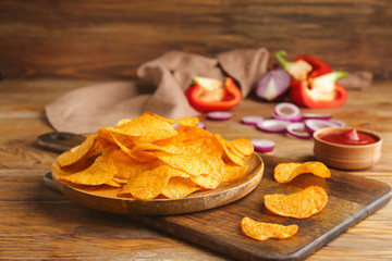 Plate with tasty potato chips on table