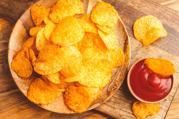 Tasty potato chips and tomato sauce on table