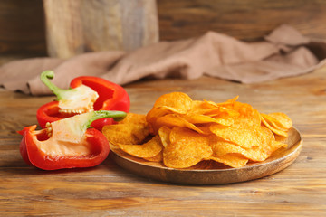 Plate with tasty potato chips and bell pepper on table