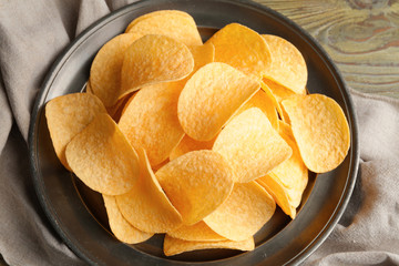 Plate with tasty potato chips on table