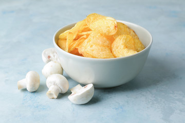 Bowl with tasty potato chips and mushrooms on table