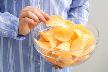 Woman with bowl of tasty potato chips, closeup
