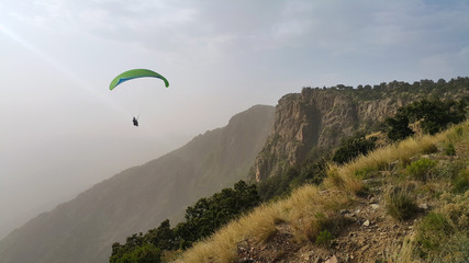 silhouette of man flying a paraglider in the blue sky - Paragliding is the recreational and competitive adventure sport of flying paragliders: lightweight, free-flying, foot-launched glider aircraft 