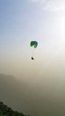 silhouette of man flying a paraglider in the blue sky - Paragliding is the recreational and competitive adventure sport of flying paragliders: lightweight, free-flying, foot-launched glider aircraft 