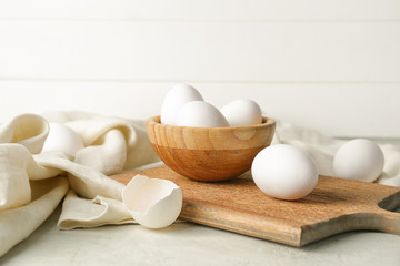 Bowl with fresh raw eggs on table