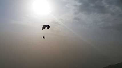 silhouette of man flying a paraglider in the blue sky - Paragliding is the recreational and competitive adventure sport of flying paragliders: lightweight, free-flying, foot-launched glider aircraft 